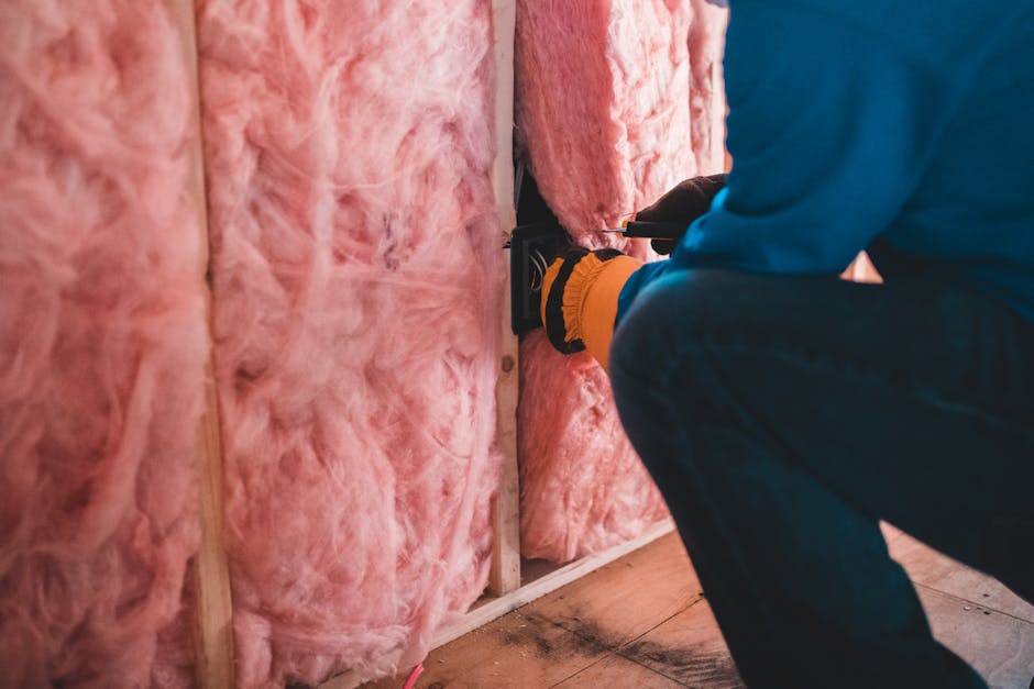 Ouvrier installant une isolation en fibre de verre rose